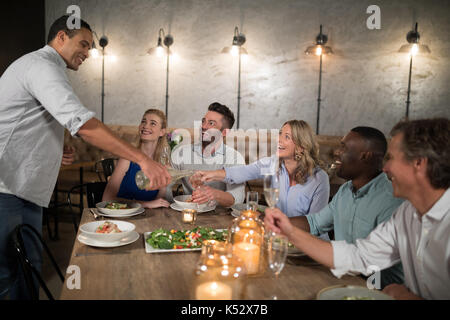 L'homme de servir le champagne à ses amis de restaurant Banque D'Images