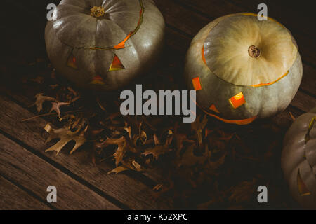 High angle view of illuminated white jack o lanterne avec les feuilles d'automne sur la table Banque D'Images