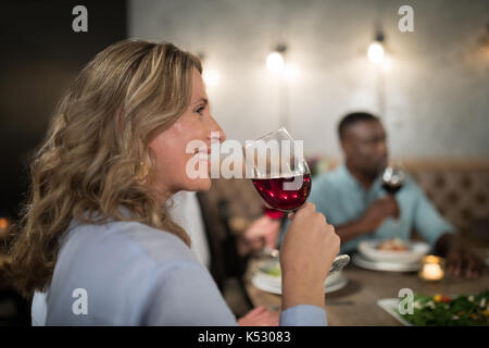 Femme ayant le vin rouge avec ses amis en arrière-plan Banque D'Images