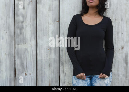 Mid section of young woman leaning on wooden wall Banque D'Images