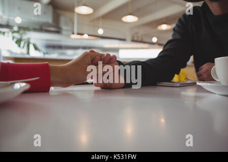 Portrait de couple holding hands at table in cafe Banque D'Images