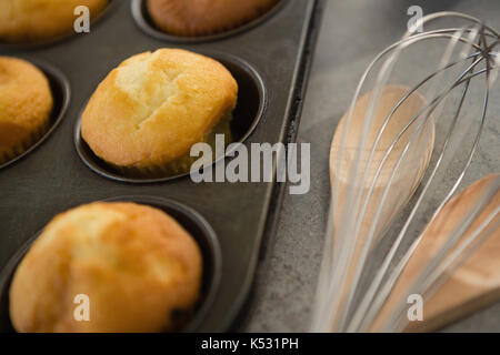 Close up de muffins dans tin par cuillère en bois et de fouet sur table Banque D'Images