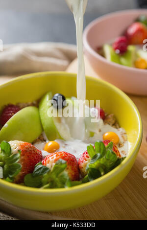 Close-up de lait est versé dans un bol de céréales pour petit déjeuner Banque D'Images