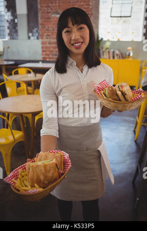 Portrait of young waitress holding paniers avec des sandwichs au cafe Banque D'Images