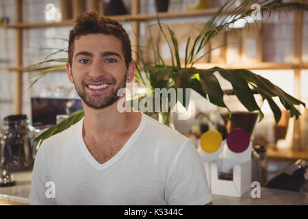 Portrait of smiling youngh man standing at cafe Banque D'Images