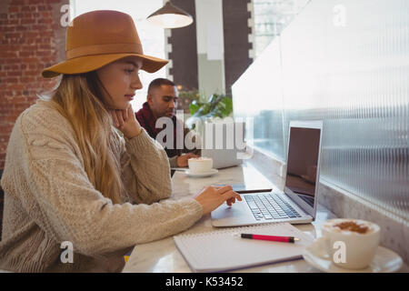 Young businesswoman using laptop at counter in cafe Banque D'Images