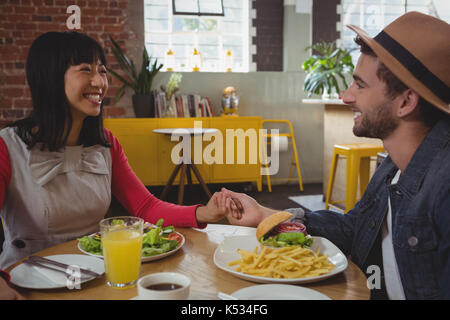 Happy young couple holding hands at cafe Banque D'Images