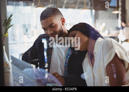 Young woman leaning on vu à travers l'épaule de l'homme en verre cafe Banque D'Images