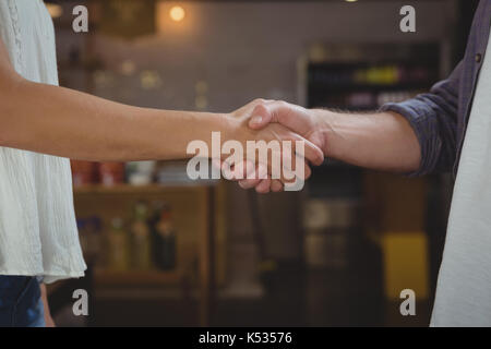 Portrait of business people shaking hands while standing at cafe Banque D'Images