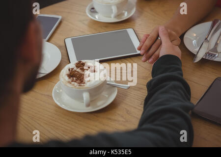 Portrait de couple holding hands par tasse de café à la table in cafe Banque D'Images