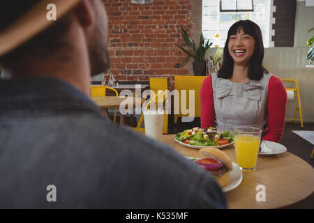 Happy young woman looking at man while sitting in cafe Banque D'Images