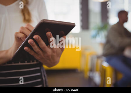 Section intermédiaire de waitress using digital tablet at cafe Banque D'Images