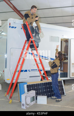 Deux électriciens l'installation de panneaux solaires sur toit rv Banque D'Images