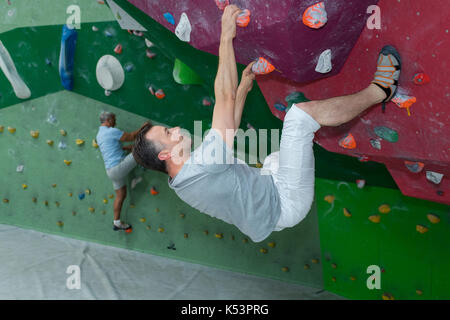 Les hommes sportif d'escalade sur un mur d'escalade Banque D'Images