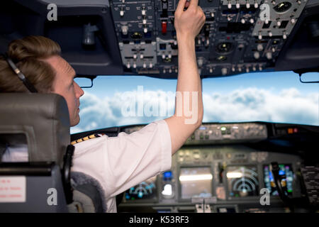 Young male pilot in airplane cockpit commandes de commutation Banque D'Images