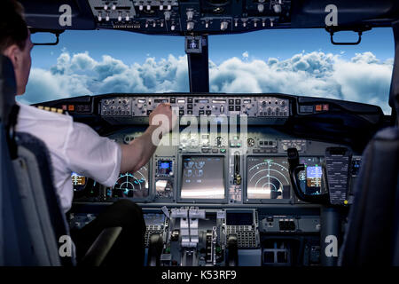 Vue arrière du jeune homme dans les commandes de commutation pilote airplane cockpit Banque D'Images