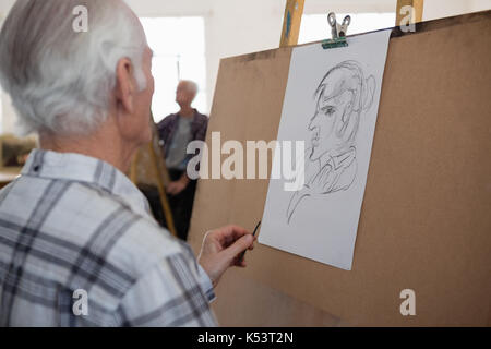 Close up of senior man dessin croquis de femme sur le papier dans la classe d'art Banque D'Images