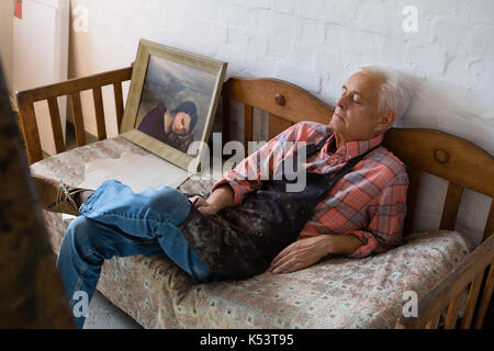 Portrait de l'artiste masculin senior relaxing on sofa in art class Banque D'Images