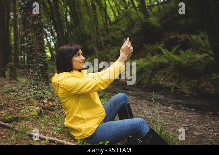 Woman with mobile phone selfies en forêt Banque D'Images