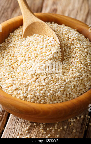 Les matières premières organiques quinoa blanc close-up dans un bol en bois sur la table verticale. Banque D'Images