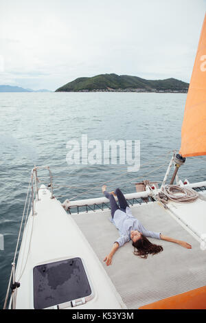 Jeune femme se reposant sur le pont du navire tout en profitant d'une croisière sur un bateau Banque D'Images