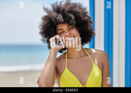 Portrait de femme jolie en bikini jaune talking on mobile Banque D'Images