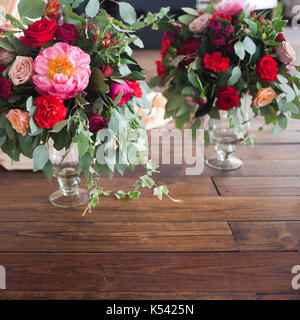 Des vases avec des bouquets de fleurs rouges sur fond de bois de plancher. Banque D'Images