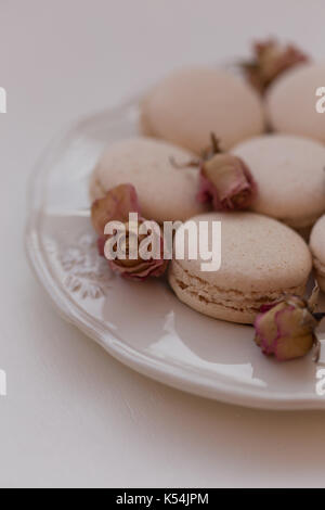 Macarons beige et rose rose séchée sur une plaque sur fond blanc tourné avec une faible profondeur de champ Banque D'Images