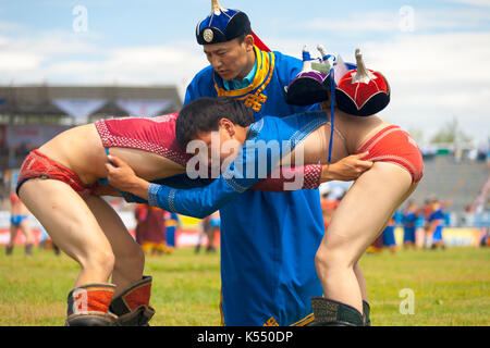 Oulan-bator, Mongolie - 11 juin 2007 : Un arbitre contrôle deux jeunes lutteurs à l'intérieur du stade sportif national au festival naadam wrestling comp Banque D'Images