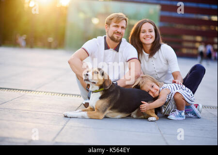 Jeune famille merveilleuse est au repos assis sur le sol. papa, maman, ma fille et beagle. Été chaud météo, bonne humeur. Banque D'Images