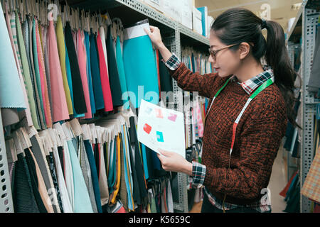 Jolie jolie femme designer de vêtements à choisir l'échantillon des matériaux et de l'usine à papier de couleur pour confirmer le plan de conception. Banque D'Images