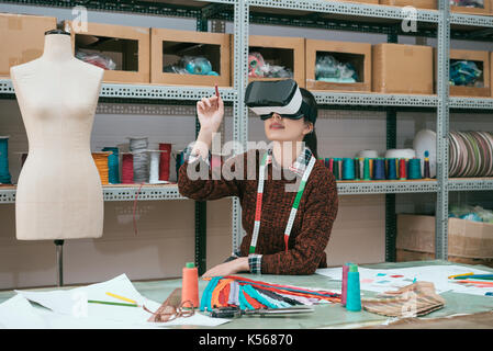Pretty woman smiling worker Using virtual reality device le visionnage en 3d plan de conception et de l'information tenir pen de toucher l'écran de simulation. Banque D'Images