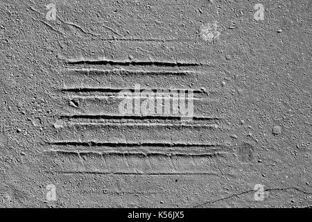 Les empreintes de pneus sur la vieille route d'asphalte fissuré dans blak et blanc Banque D'Images