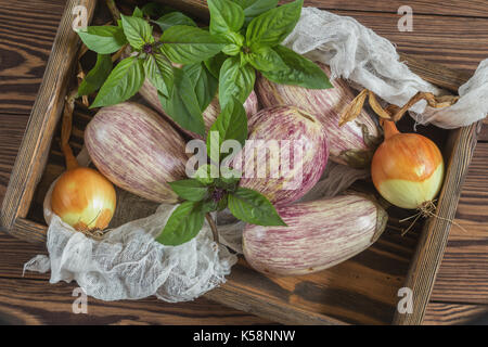 Graffiti violet aubergine, l'oignon vert et le basilic frais dans une boîte en bois dans un fond de bois dans un style rustique, selective focus Banque D'Images