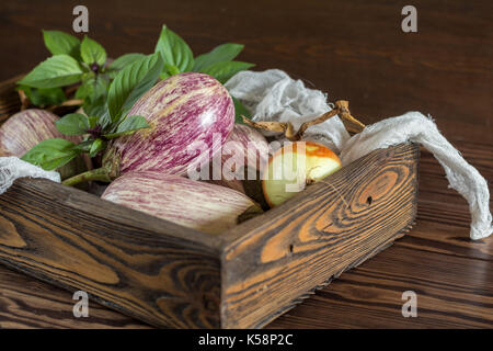 Graffiti violet aubergine, l'oignon vert et le basilic frais dans une boîte en bois dans un fond de bois dans un style rustique, selective focus Banque D'Images