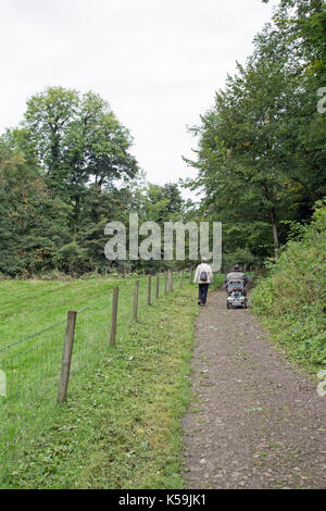 Septembre 2017, un couple, une mobilité et en utilisant une aide à la mobilité voyager sur un chemin dans la campagne. Banque D'Images