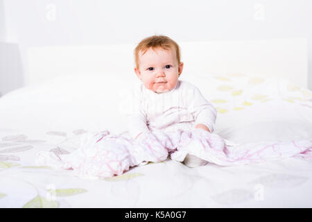 Portrait d'un bébé rampant sur le lit dans sa chambre Banque D'Images