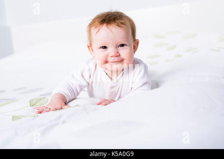 Portrait d'un bébé rampant sur le lit dans sa chambre Banque D'Images