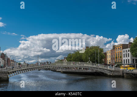 Dublin, Irlande - août 7, 2017 : metal historique ha'penny passerelle au-dessus de la rivière Liffey sous ciel bleu avec des nuages blancs géants. Des gens qui marchent. f Banque D'Images