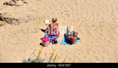 Couple bronzé à bronzer sur une plage Minorque Minorque espagne Banque D'Images