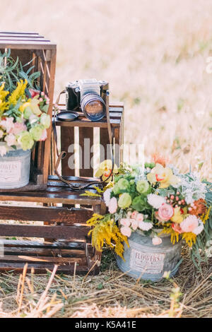 Le gros plan de la photo verticale boxex docerated en bois avec des fleurs dans les bacs et old vintage caméra dans la zone ensoleillée. Banque D'Images