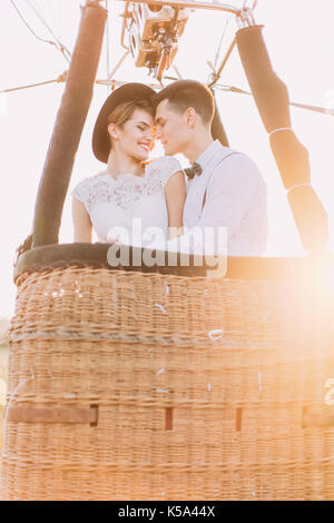 Close-up portrait of smiling le côté vintage habillé newlyweds hugging dans le airballoon panier pendant la journée ensoleillée. Banque D'Images