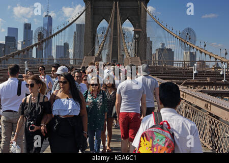 Des foules de touristes à pied sur le pont de Brooklyn dans un ciel ensoleillé de la fête du travail avec la partie basse de Manhattan en arrière-plan Banque D'Images