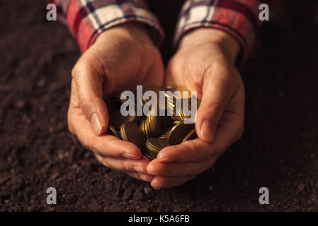 Poignée de pièces, femme agronome faisant l'argent à partir de l'activité agricole Banque D'Images