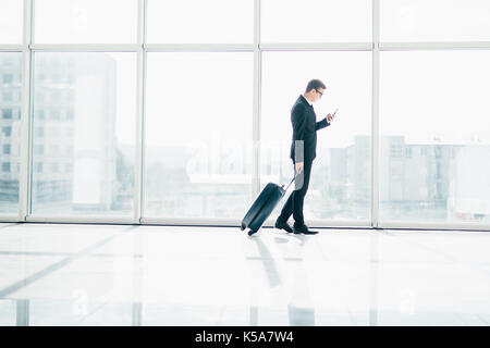 Homme d'affaires à l'aéroport international déménagement à la borne d'embarquement pour voyager en avion voyage avec phone dans la main Banque D'Images