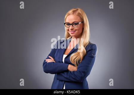 Une belle jeune businesswoman standing avec confiance et portant des lunettes Banque D'Images