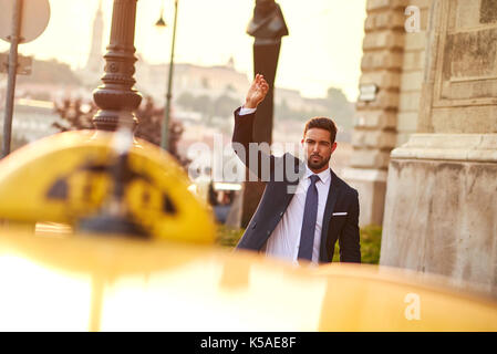 Un beau jeune businessman waving pour un taxi Banque D'Images