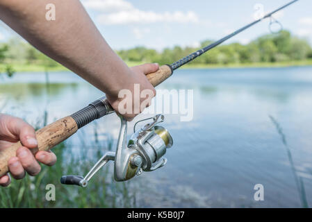 Close-up de mains d'un garçon avec une canne à pêche Banque D'Images