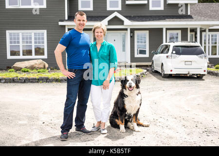 Cheerful couple standing in front of new house Banque D'Images