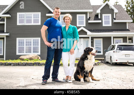 Cheerful couple standing in front of new house Banque D'Images